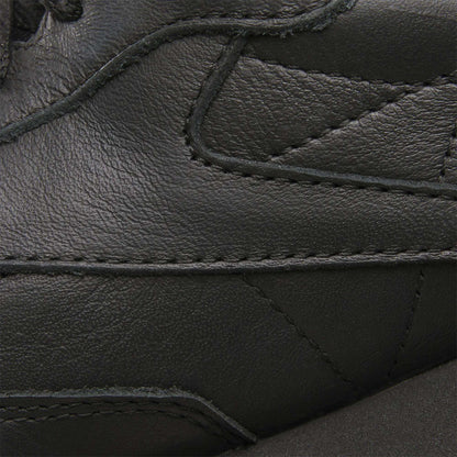 Close-up of Reebok Classic Leather Shoes in black, highlighting the detailed stitching, durable leather texture, and retro style with overlapping panels.