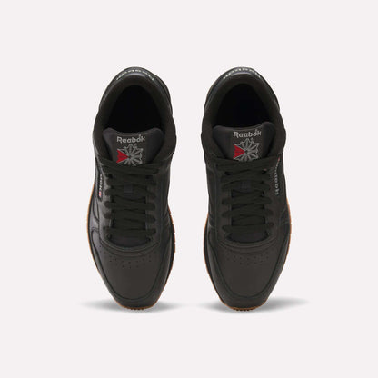 Top view of a pair of Reebok Classic Leather Shoes in black with black laces, gum soles, and the Reebok logo on the tongues and sides. Durable leather and retro design stand out against a white background.