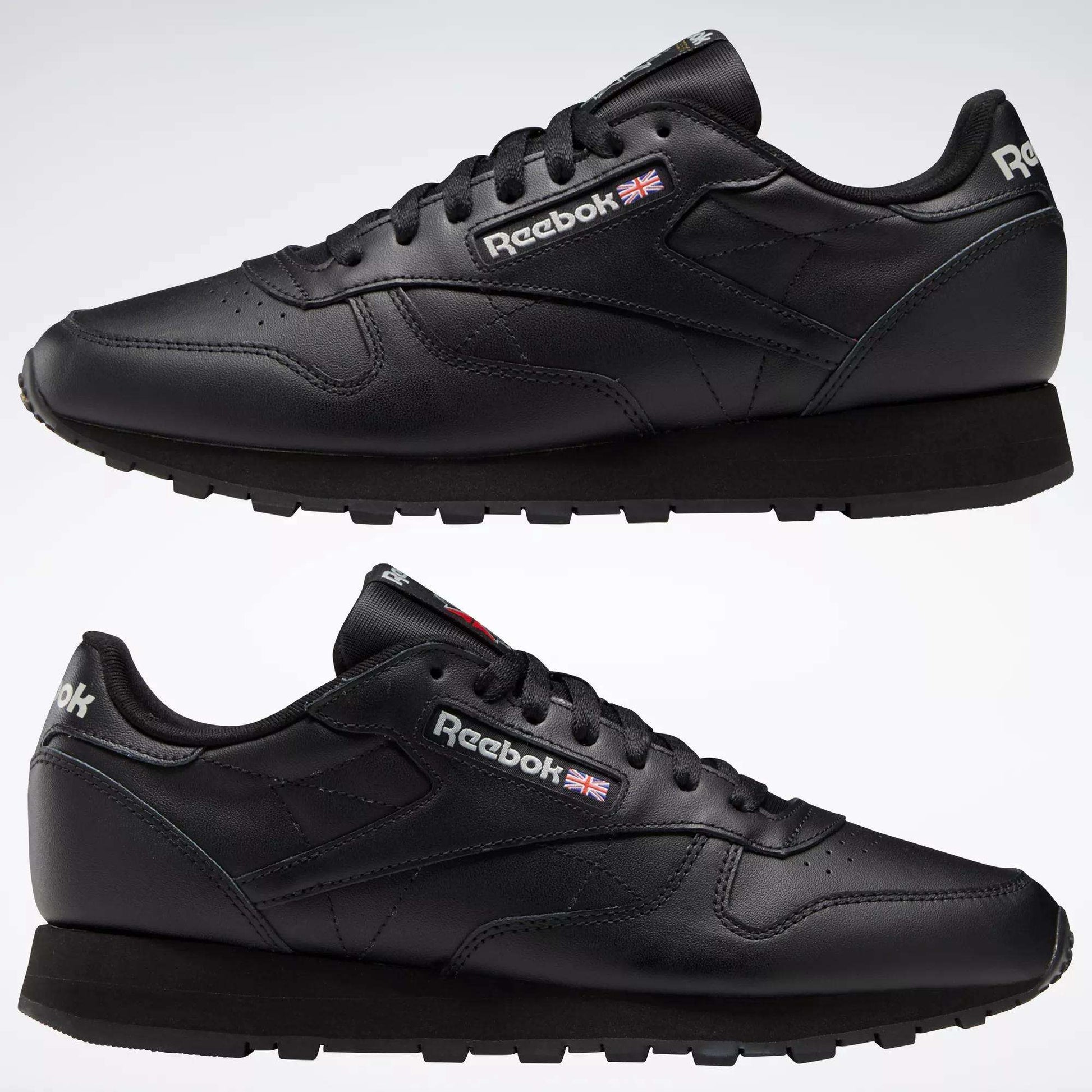 Two Reebok Classic Leather Shoes in black are displayed side by side on a white background, featuring the Reebok logo and British flag near the laces, minimalist stitching, and black rubber soles.