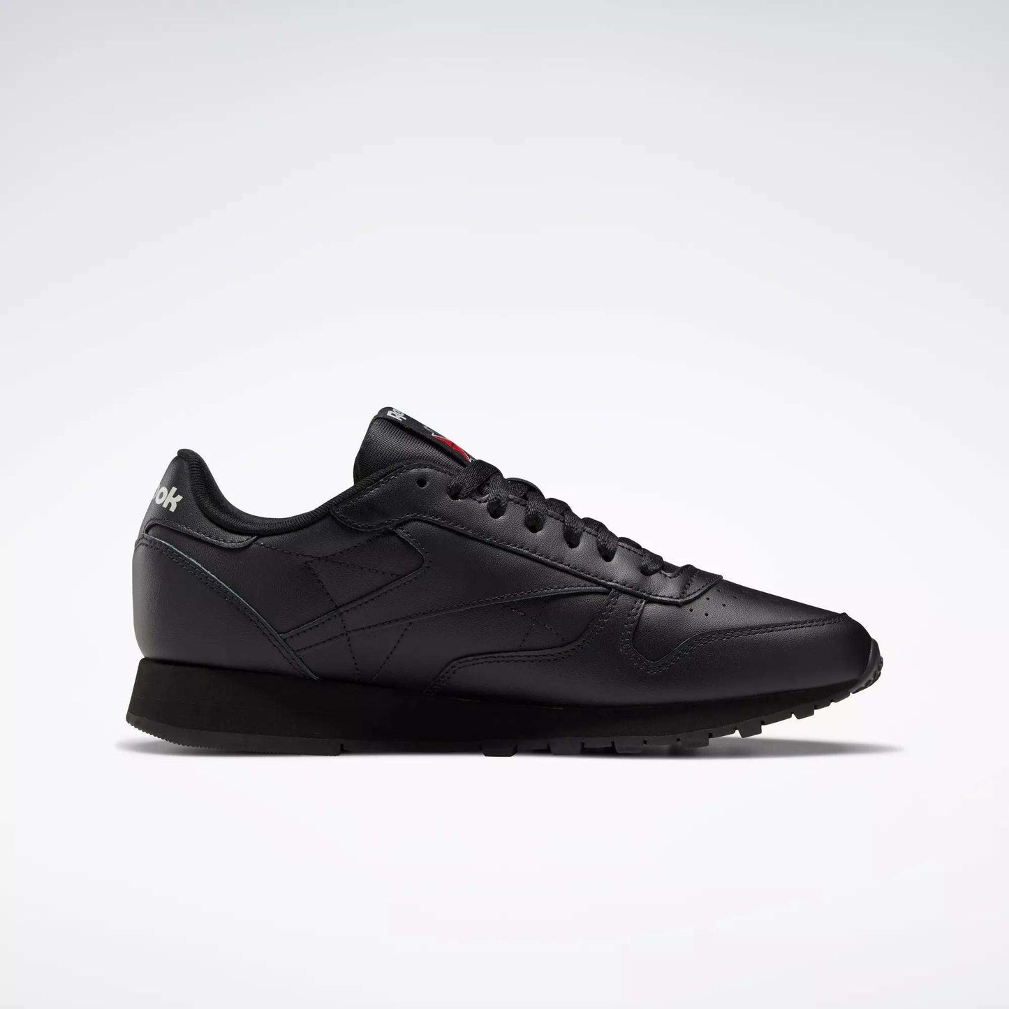 A side profile of the Reebok Classic Leather Shoes is shown on a white background, featuring a sleek black design with matching laces, stitching accents, and a durable leather trainer sole.