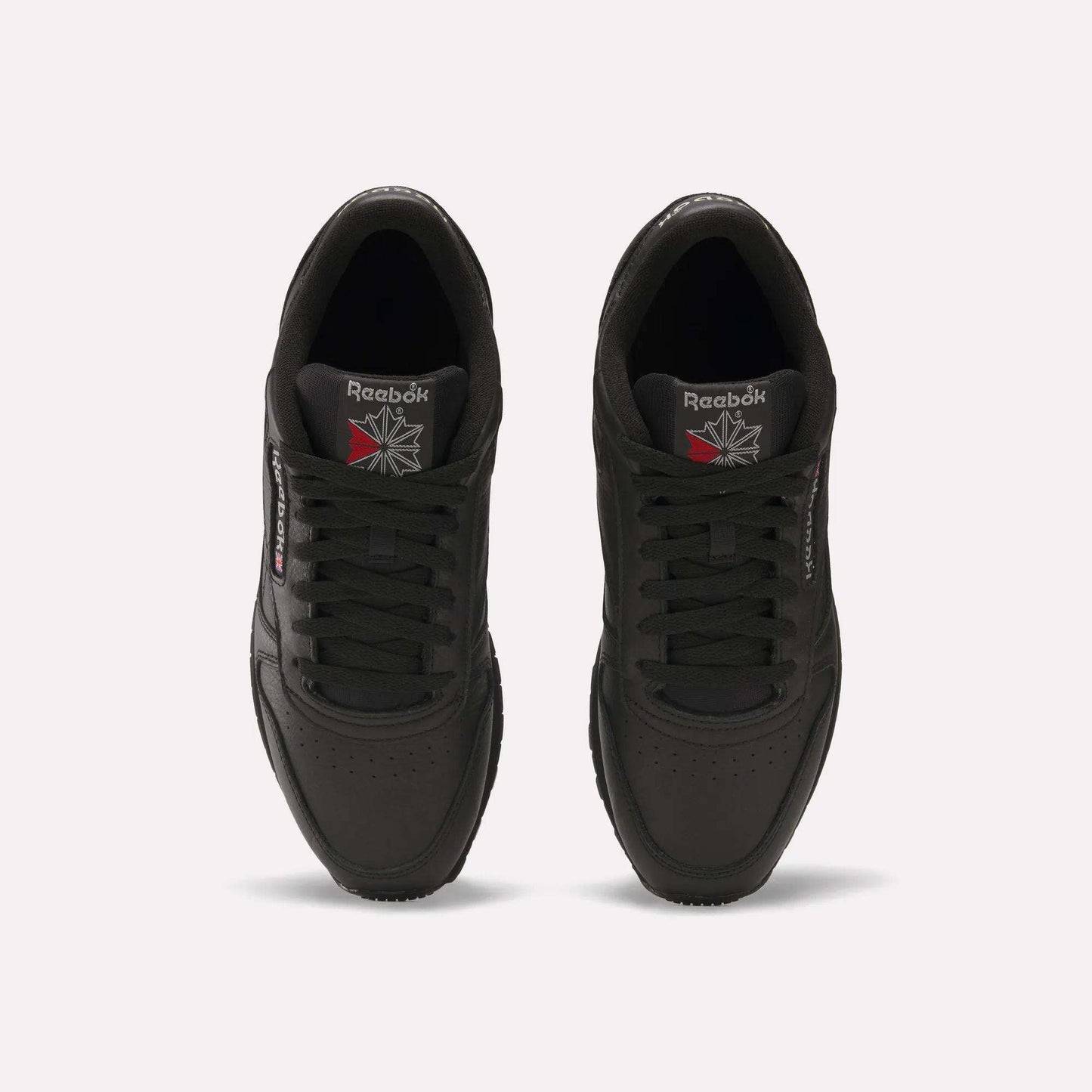Top view of Reebok Classic Leather Shoes in black, featuring a durable leather upper and iconic Reebok logos on the tongue and side, displayed against a plain white background.