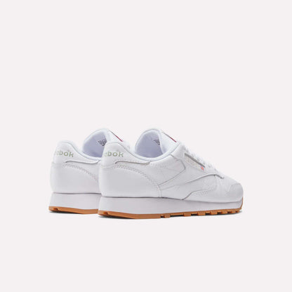 A pair of Women's Classic Leather Shoes by Reebok, featuring a cushioned midsole and light brown rubber soles, shown from the back and side against a plain light background.
