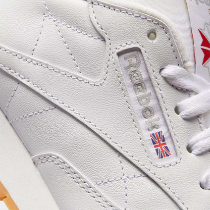Close-up of Reebok Women's Classic Leather Shoes, highlighting the brand logo, Union Jack patch, white laces, detailed stitching, and cushioned midsole.