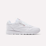 The Women's Classic Leather Shoes by Reebok feature white laces, a low-cut design, minimal stitching, a cushioned midsole, and the iconic Reebok logo with British flag on the side. The sole is also white.