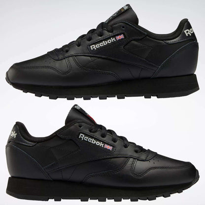 Two black Reebok Women's Classic Leather Shoes are shown in side view, one above the other, on a white background. The cushioned midsole, Reebok logo, and Union Jack flag appear on the sides and heel.
