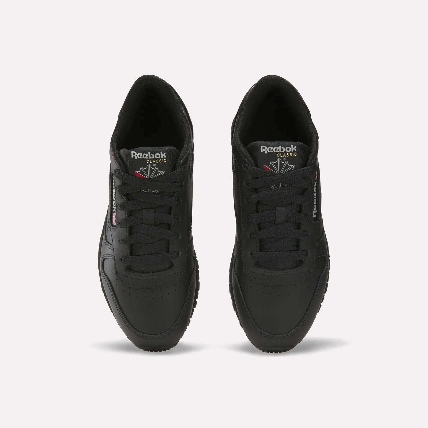 A pair of Reebok Women's Classic Leather Shoes in black, seen from above with visible laces, the Reebok logo on the tongue, side branding, and a cushioned midsole, all displayed on a plain white background.