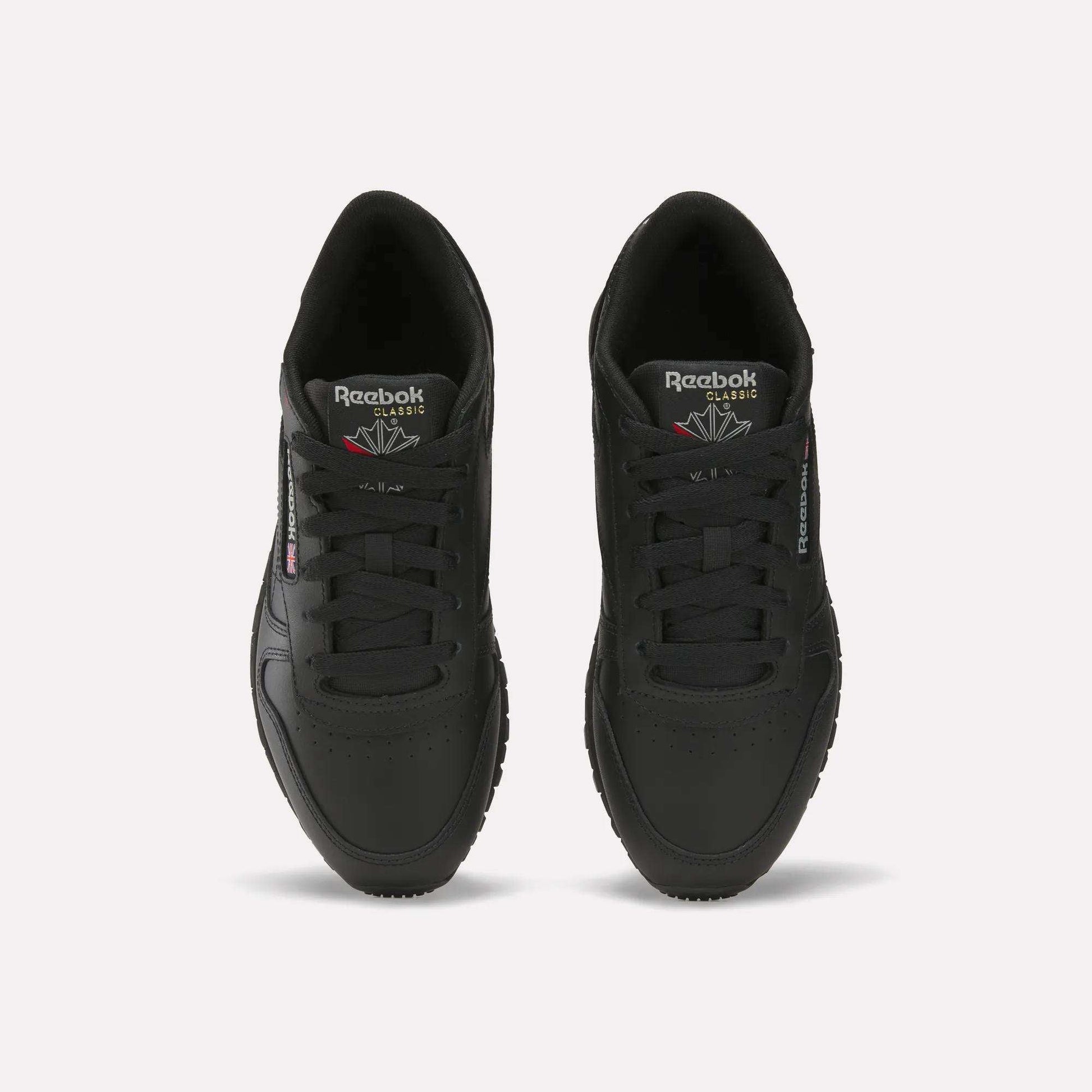 A pair of Reebok Women's Classic Leather Shoes in black, seen from above with visible laces, the Reebok logo on the tongue, side branding, and a cushioned midsole, all displayed on a plain white background.