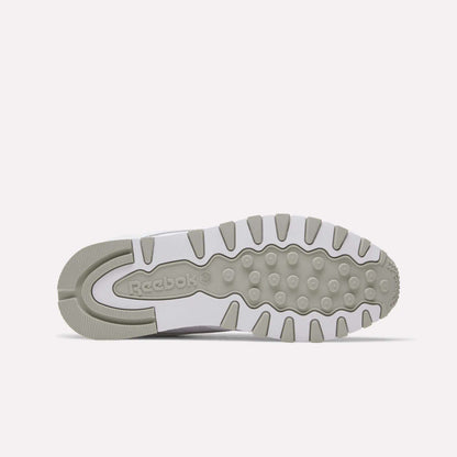 The image displays the sole of Reebok Classic Leather Shoes, combining light gray and white hues with textured grips and the Reebok logo embossed near the heel.