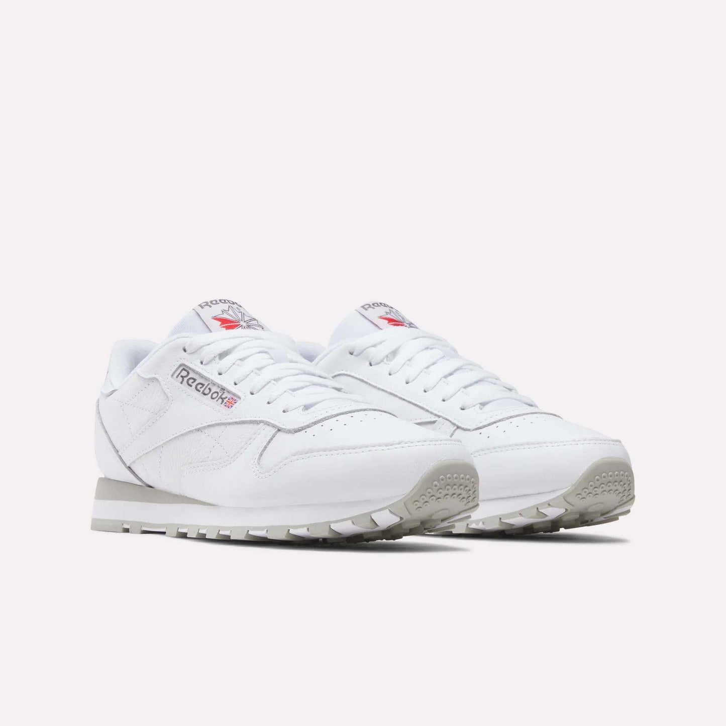 Reebok Classic Leather Shoes in white, featuring grey soles and the iconic Reebok logo with Union Jack on the side and tongue, are displayed on a plain white background for a timeless retro look.