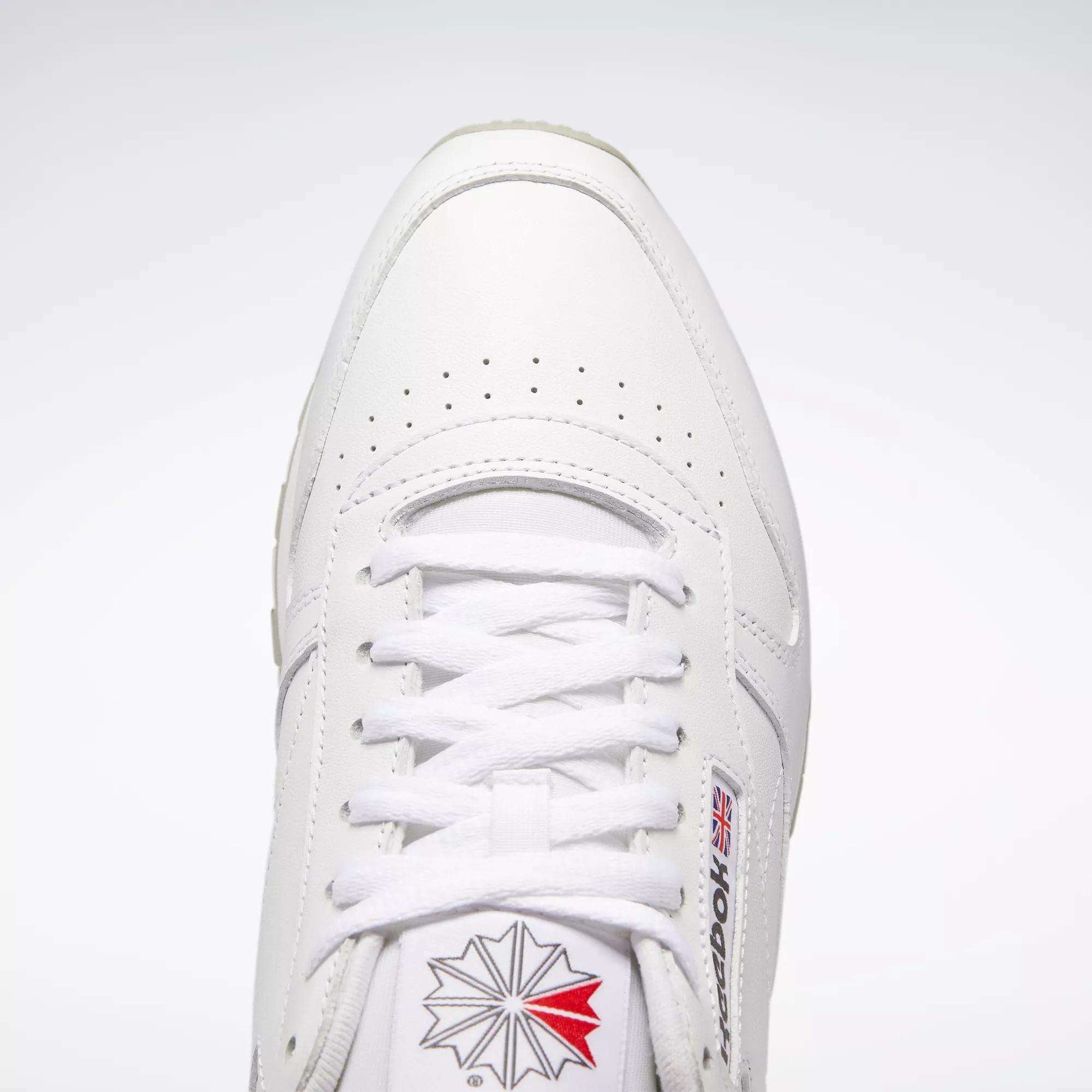 Top view of Reebok Classic Leather Shoes in white, retro style with durable leather, white laces, toe perforations, and the Reebok logo with British flag on the side and tongue against a light background.