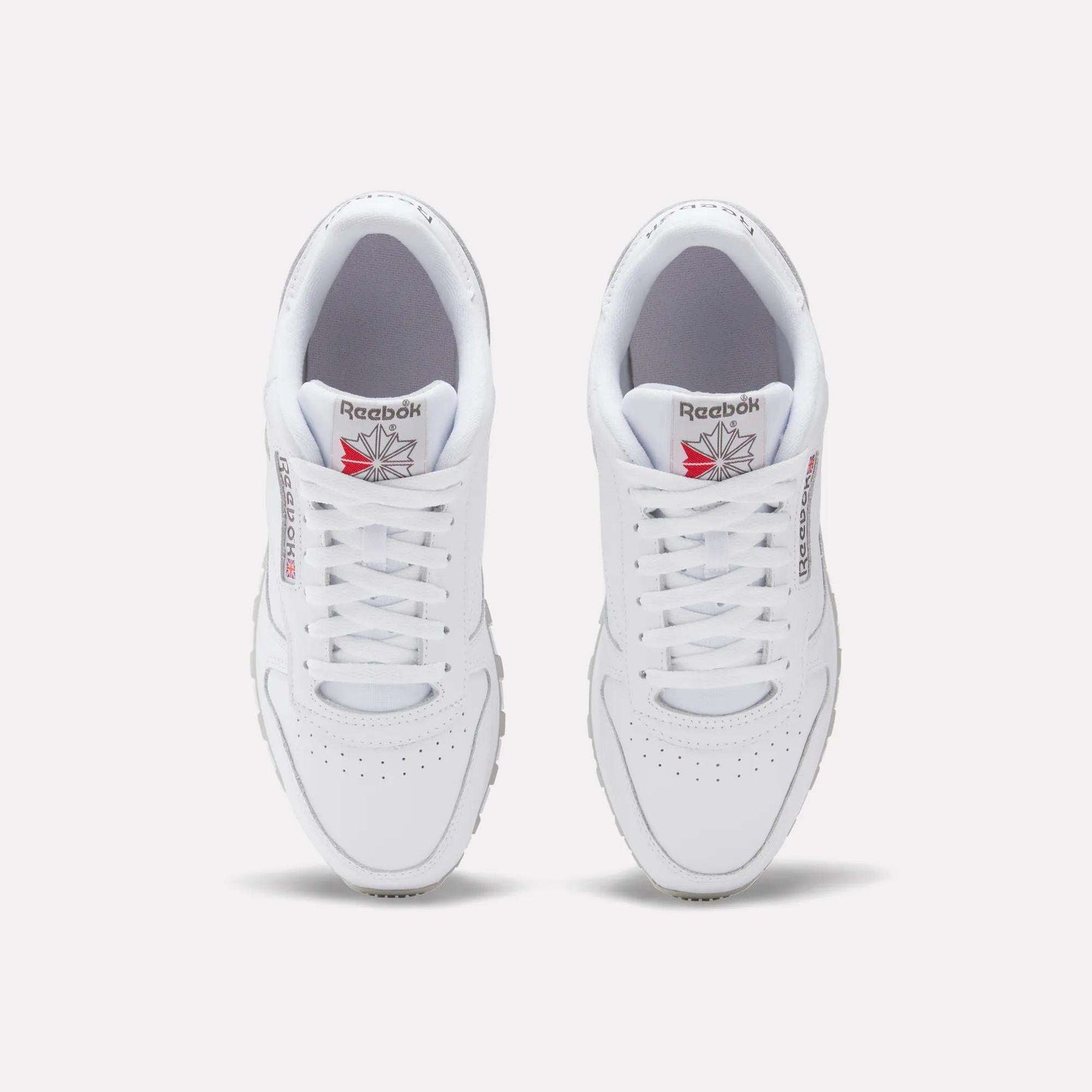 A top-down view of Reebok Classic Leather Shoes, featuring white uppers, laces, and the Reebok logo with red detailing on each tongue.