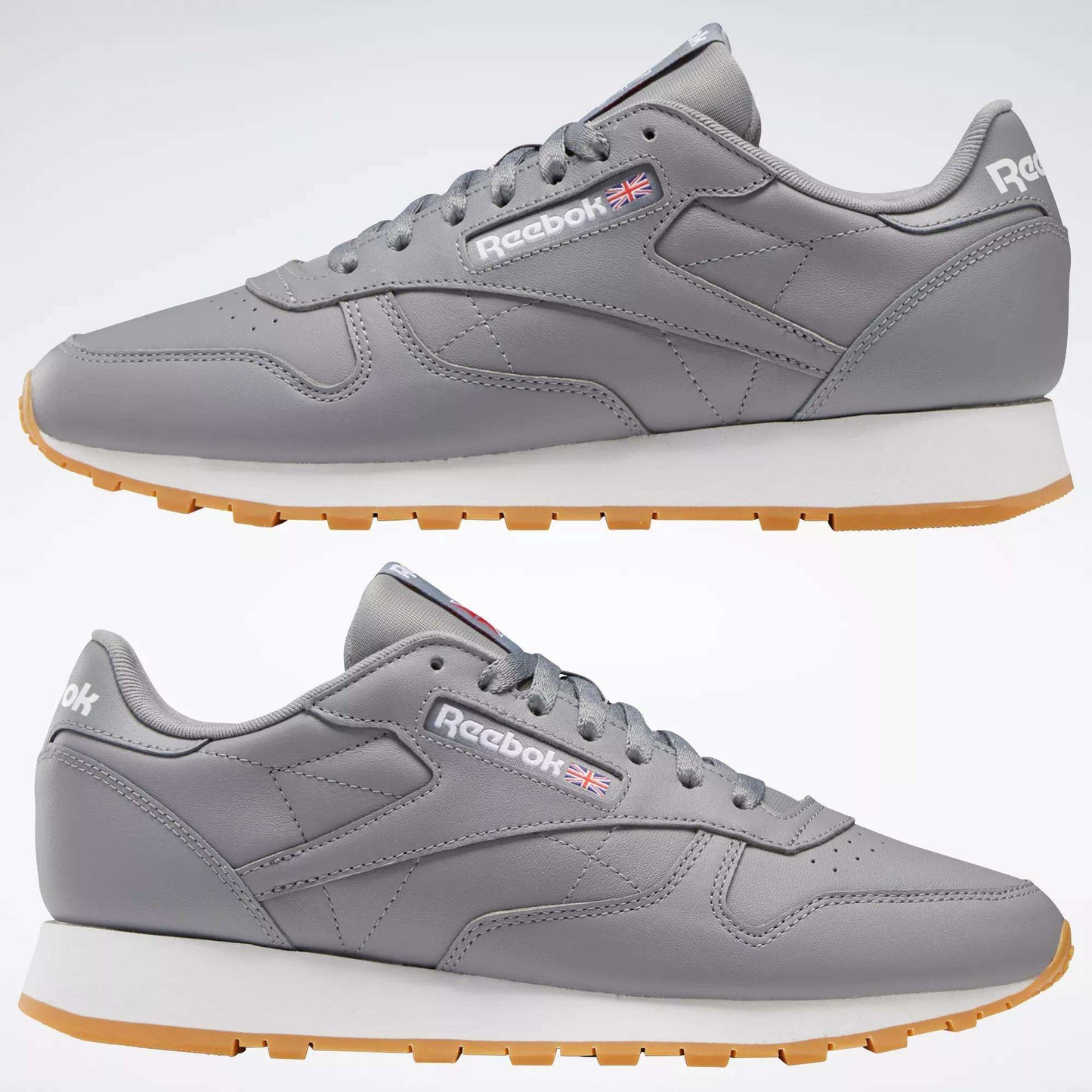 The Reebok Classic Leather Shoes feature gray leather uppers, white midsoles, and light brown rubber outsoles. Seen from the side against a plain background, they display the Reebok logo and UK flag on the sides.