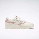 The Reebok Women's Club C Double Revenge Shoes are white sneakers with pale pink accents and logo, featuring a leather upper, lace-up closure, court-inspired design, and rubber sole, displayed on a plain white background.