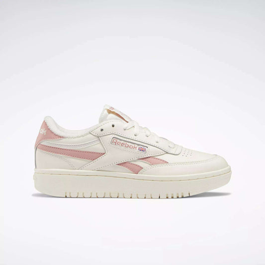 The Reebok Women's Club C Double Revenge Shoes are white sneakers with pale pink accents and logo, featuring a leather upper, lace-up closure, court-inspired design, and rubber sole, displayed on a plain white background.