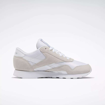 The Women's Classic Nylon Shoes by Reebok feature a white and light gray design with suede and mesh details, white laces, a flat rubber sole, and a low profile—shown from the side against a plain white background.