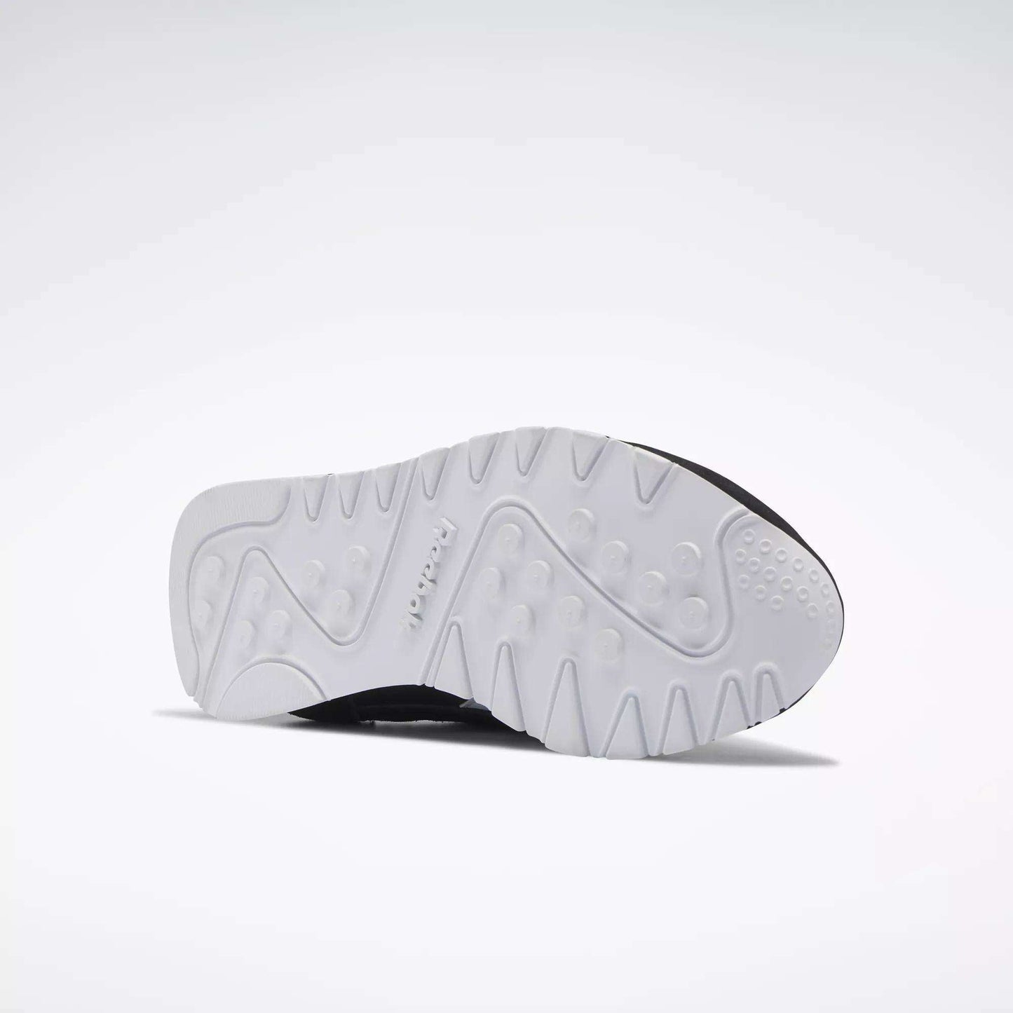 A white sole with textured patterns and raised grips is shown against a plain background, highlighting the Reebok logo—ideal for Women's Classic Nylon Shoes by Reebok and perfect as stylish everyday sneakers.