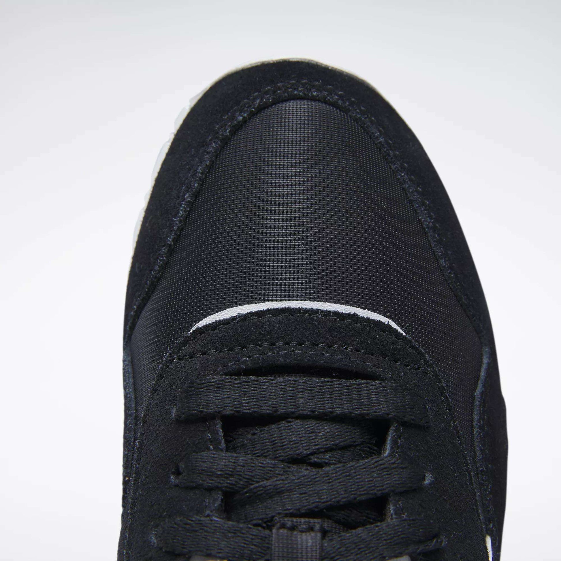 Close-up top view of the front of a black Reebok Women's Classic Nylon Shoe with black laces and a textured, rounded toe cap, shown against a plain white background.