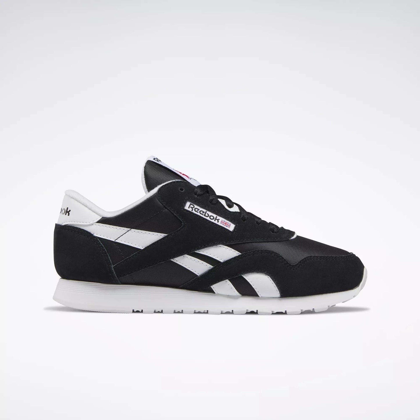 Side view of Reebok Women's Classic Nylon Shoes in black and white, featuring a white sole, black upper, and white details. These iconic sneakers are a versatile everyday choice for women, set against a simple light background.