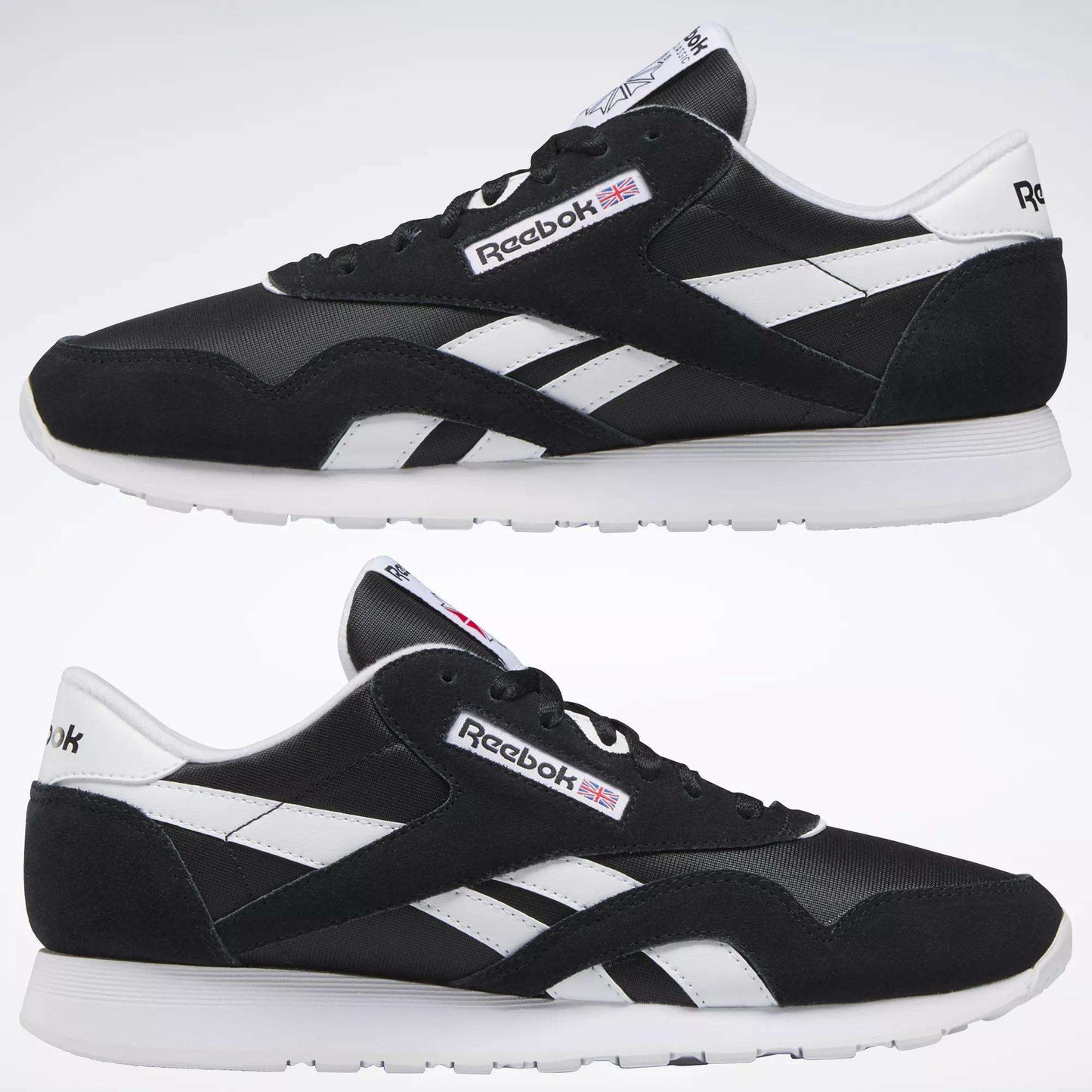 Two black Reebok Men's Classic Nylon Shoes with white soles and side stripes are shown side by side on a plain background. The Reebok logo and a small UK flag appear on the sides and tongue of these classic sneakers.