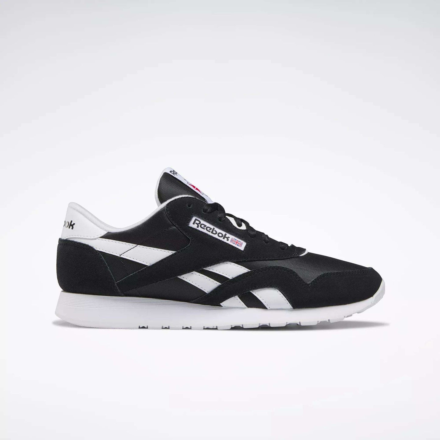 The Reebok Men's Classic Nylon Shoes in black and white feature white side stripes, a white sole, and signature Reebok logos—ideal everyday sneakers for men—displayed in a side profile on a plain light background.