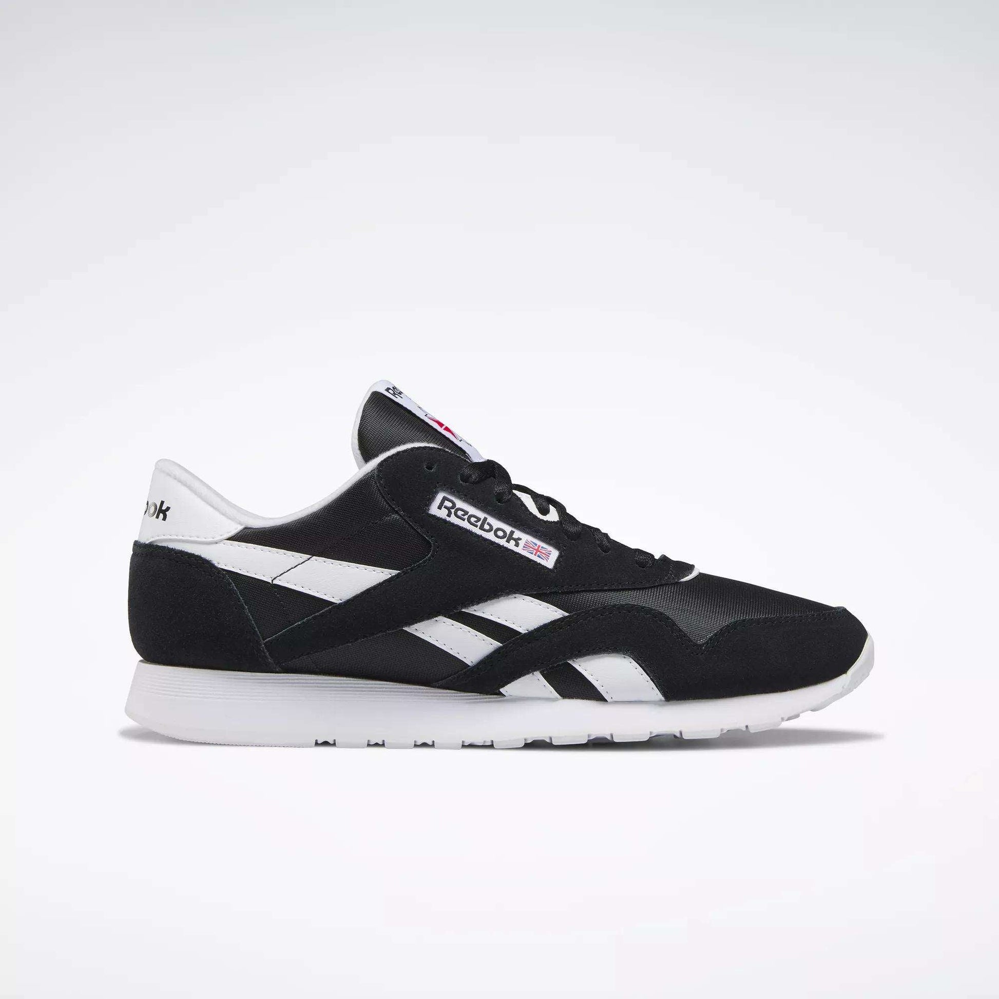 The Reebok Men's Classic Nylon Shoes in black and white feature white side stripes, a white sole, and signature Reebok logos—ideal everyday sneakers for men—displayed in a side profile on a plain light background.