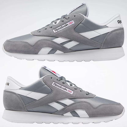 The Reebok Men's Classic Nylon Shoes are shown in gray and white from both sides on a plain white background, featuring a durable nylon upper, white laces, a white sole, and the iconic Reebok logo with a small British flag.