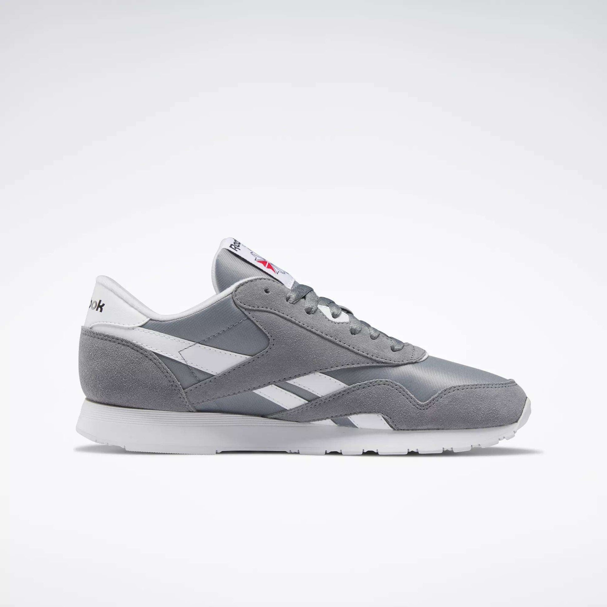 The Reebok Men's Classic Nylon Shoes in gray and white feature a nylon upper with leather accents, white sole, and laces; a timeless choice for everyday wear, shown from the side on a plain light background.