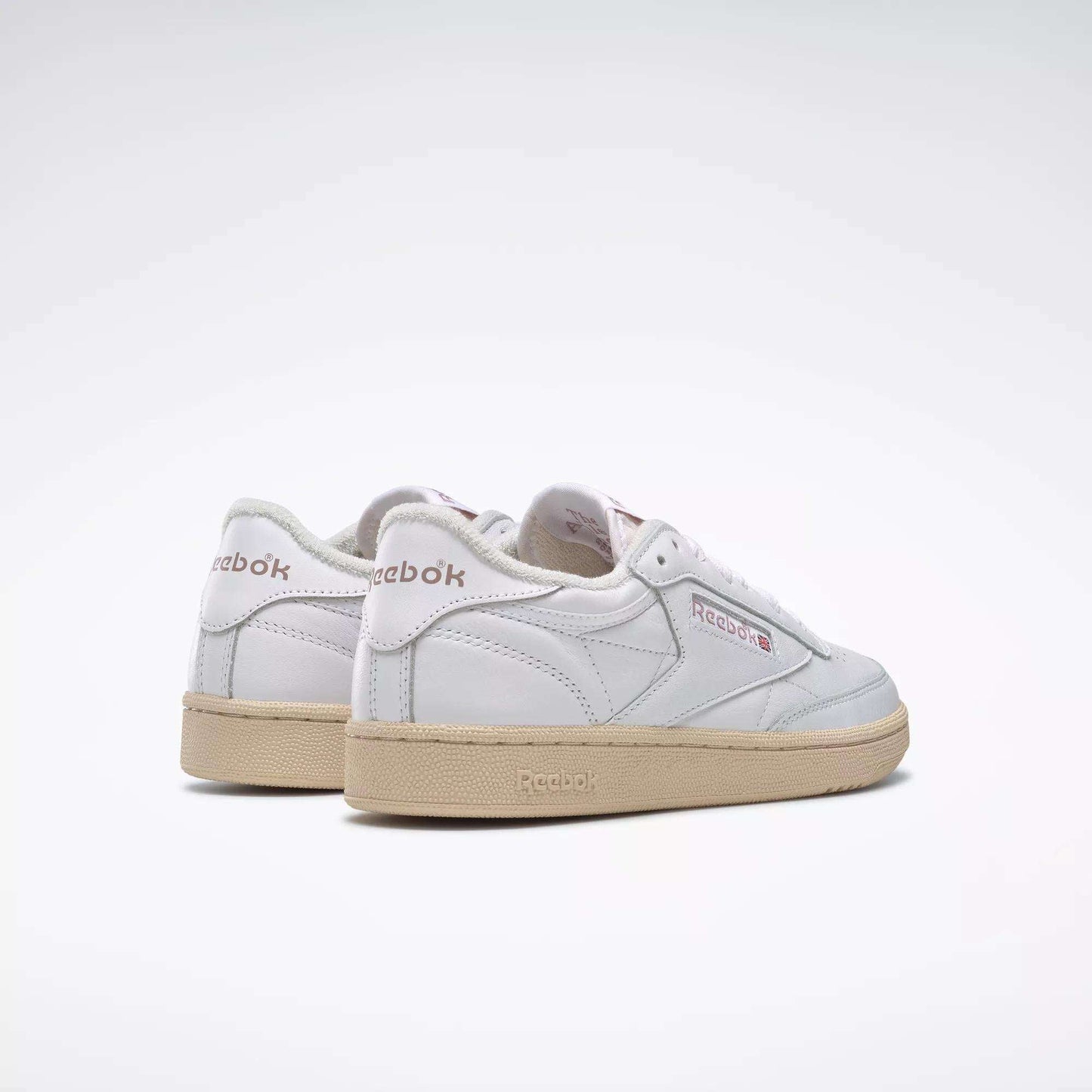 A pair of Women's Club C 85 Vintage Shoes by Reebok, in white leather with beige soles, is displayed on a light background. The Reebok logo appears on the side and heel, with the left shoe positioned slightly ahead of the right.