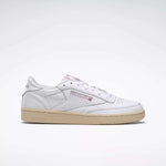 A side view of a white Reebok Women's Club C 85 Vintage Shoe with a beige sole, featuring the Reebok logo and Union Jack on the side, set against a plain light gray background.