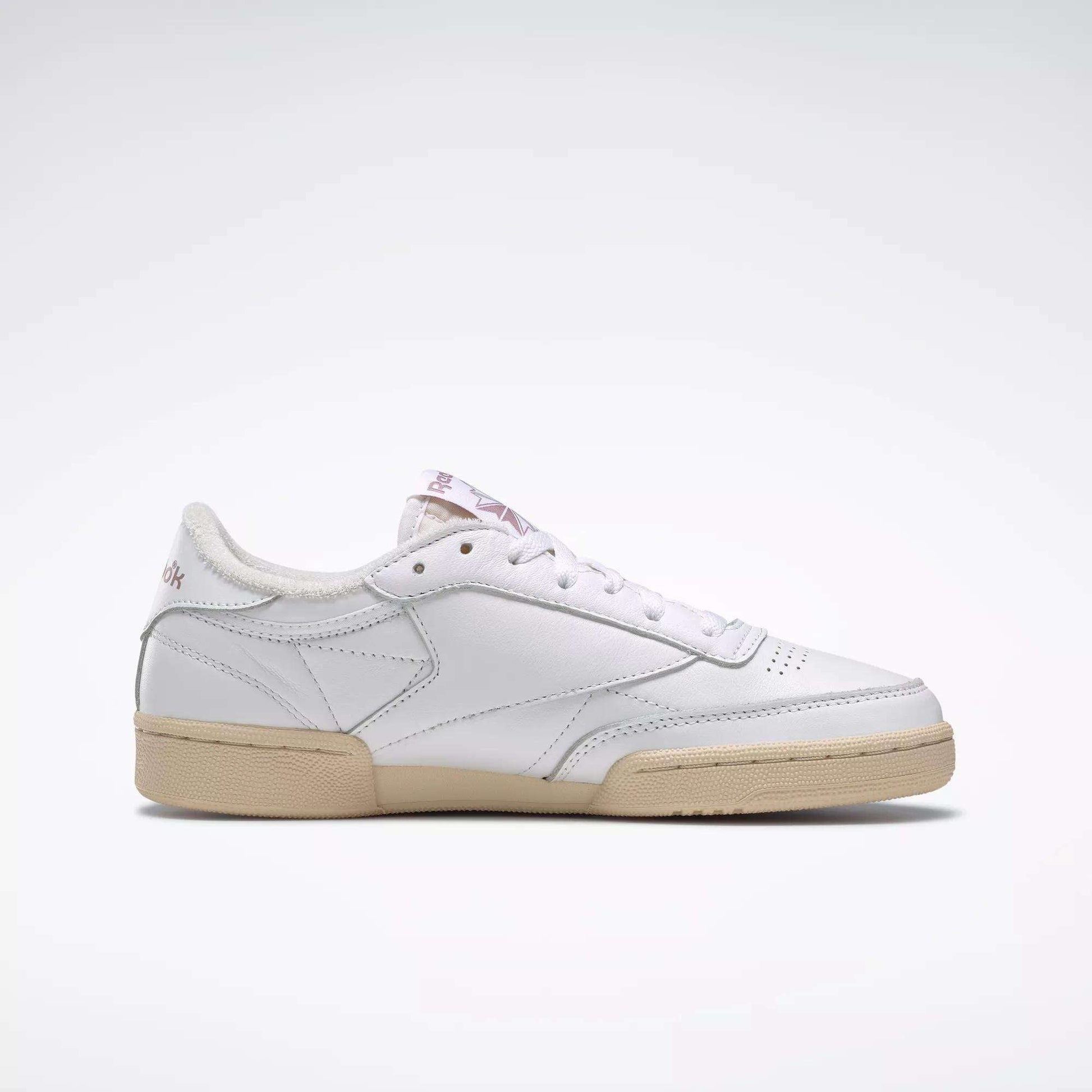 The Reebok Women's Club C 85 Vintage Shoes are white leather sneakers with a beige rubber sole, subtle stitching, and a low-cut design. Shown in side profile on a plain white background.