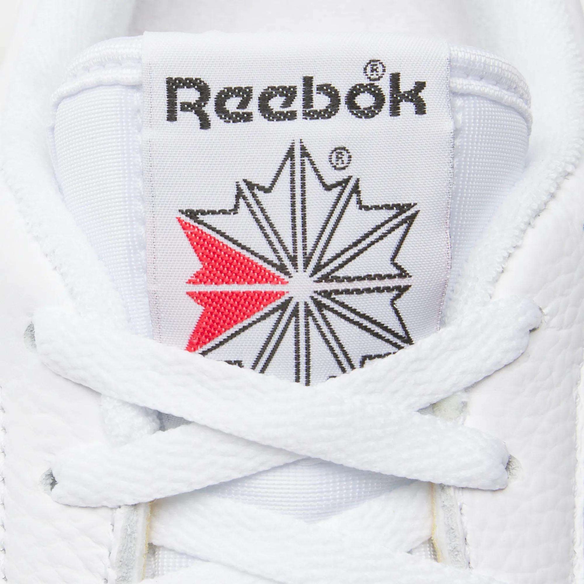 Close-up of the Reebok logo and starburst on the tongue of Men's Club C 85 Shoes by Reebok. White laces and a red accent highlight these classic men's leather sneakers.