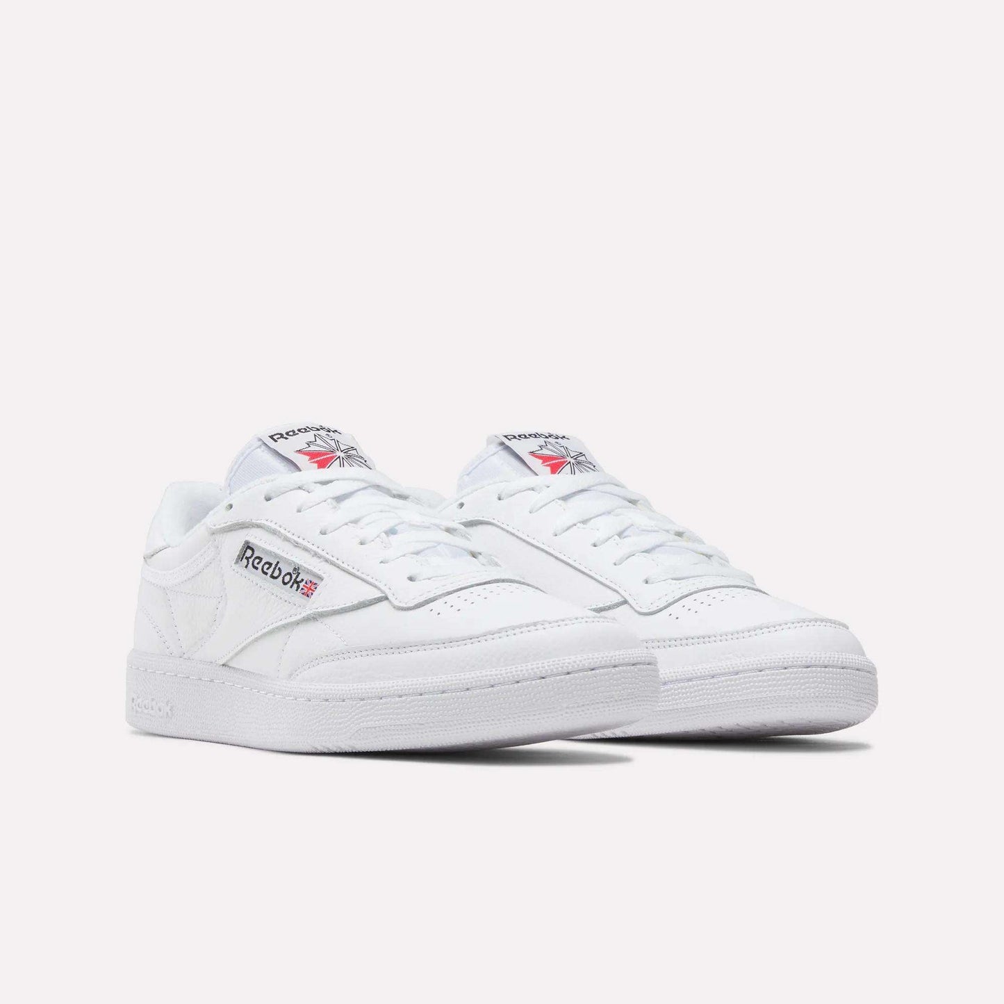 A pair of Reebok Club C 85 Shoes in white leather with low tops, showing the Reebok logo and Union Jack on the side. Inspired by classic tennis styles, displayed against a plain white background.