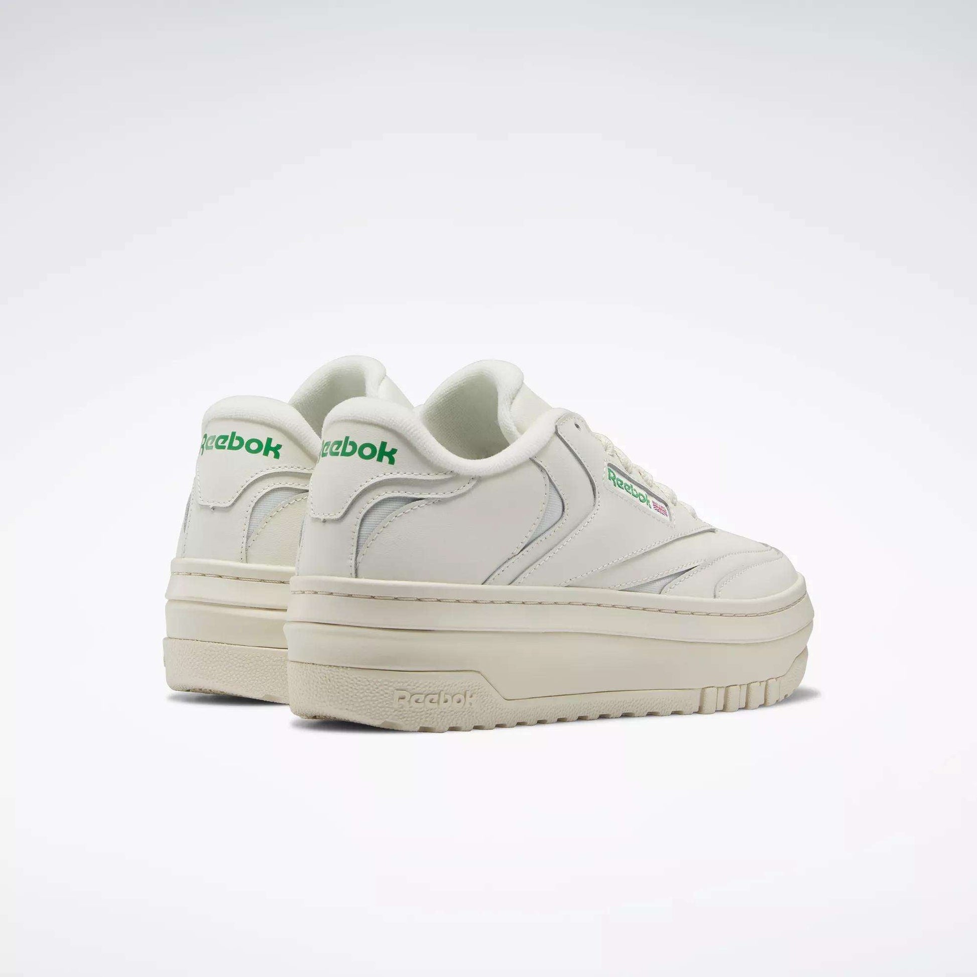 The Women's Club C Extra Shoes by Reebok feature a white upper, platform midsole, thick off-white soles, and green Reebok logos on the side and heel, shown against a plain white background.