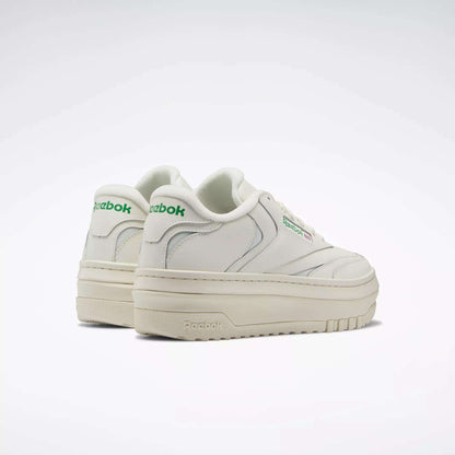The Women's Club C Extra Shoes by Reebok feature a white upper, platform midsole, thick off-white soles, and green Reebok logos on the side and heel, shown against a plain white background.