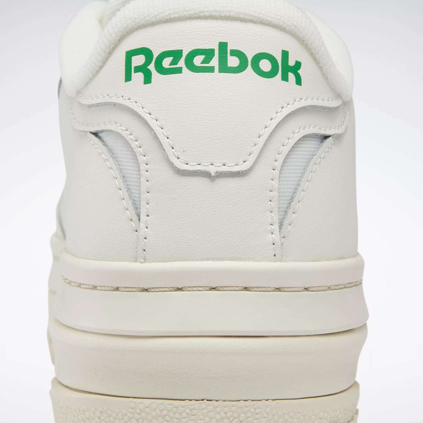 Close-up of the heel on Women's Club C Extra Shoes by Reebok, featuring green Reebok branding on the back, detailed stitching, and a glimpse of the white platform midsole.