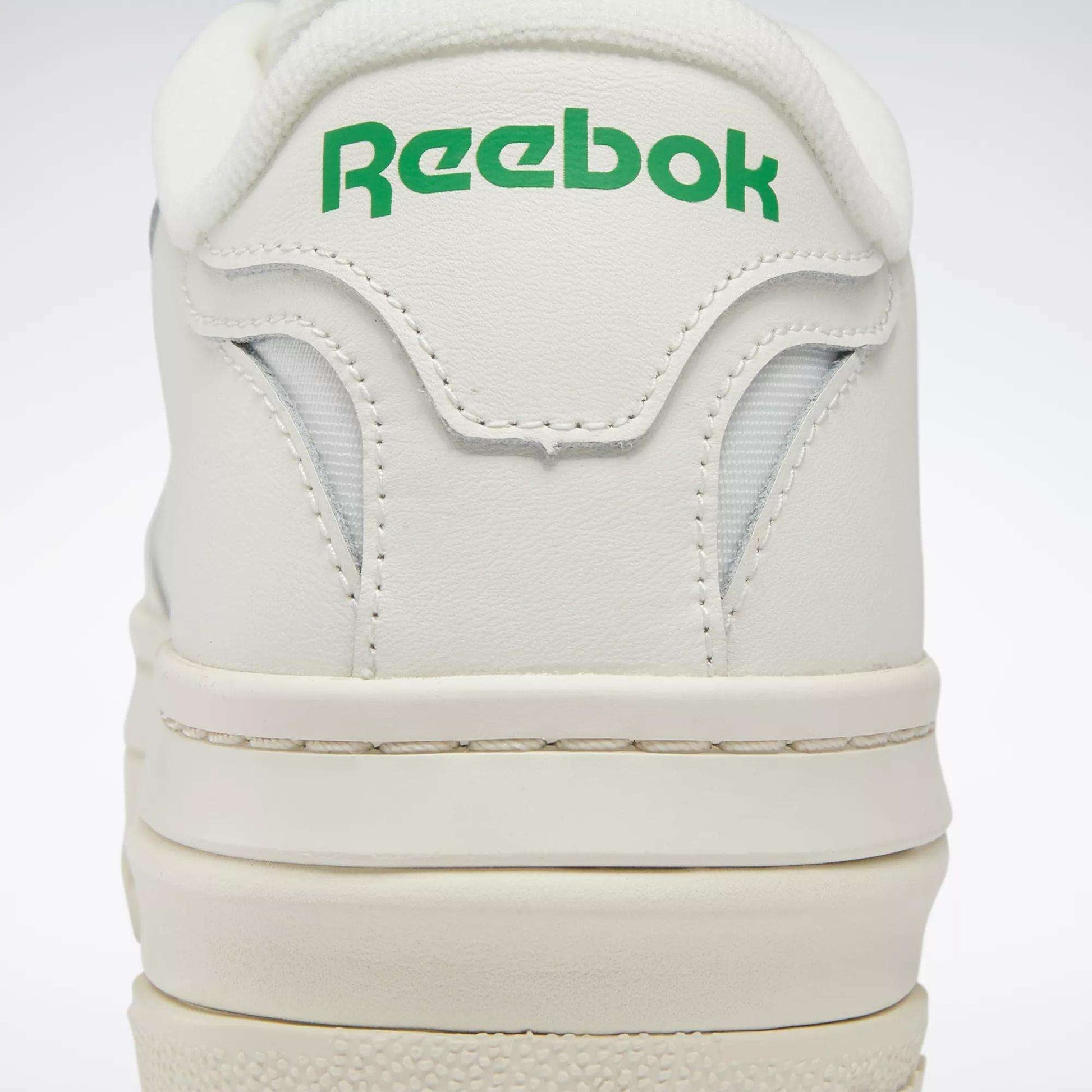 Close-up of the heel on Women's Club C Extra Shoes by Reebok, featuring green Reebok branding on the back, detailed stitching, and a glimpse of the white platform midsole.