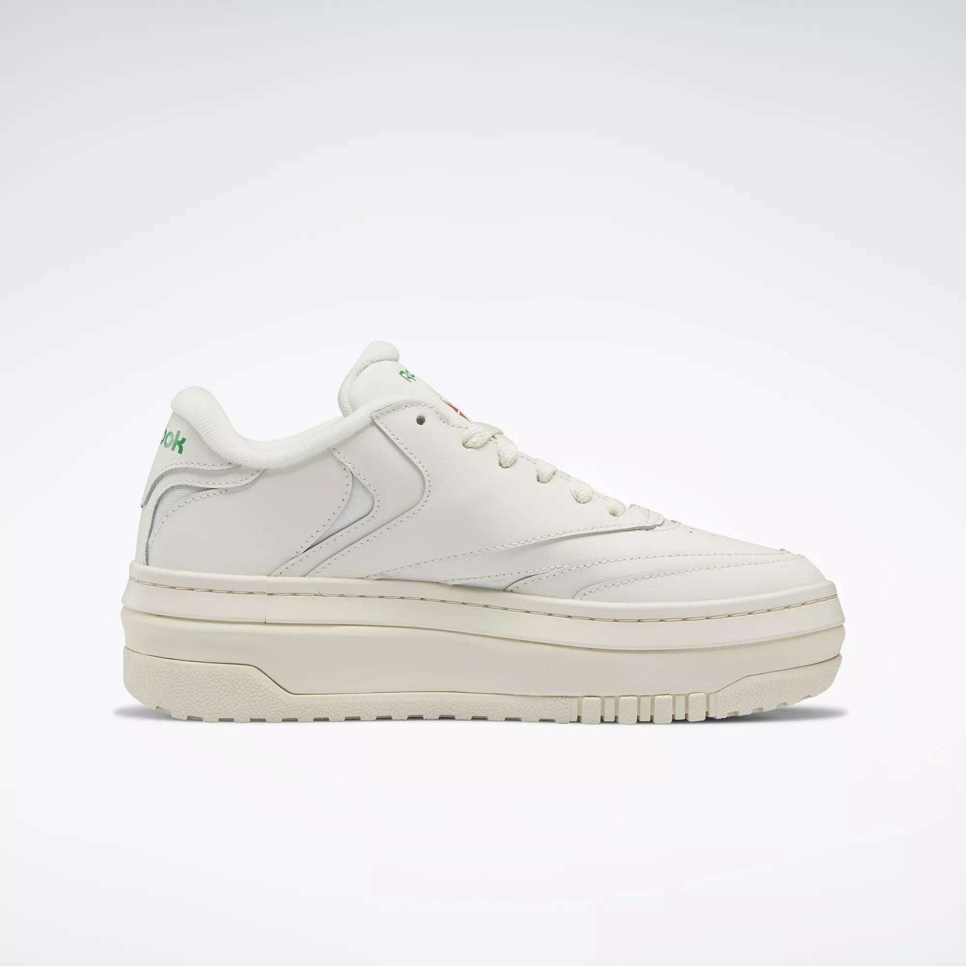 The Reebok Women’s Club C Extra Shoes feature a white upper, thick platform midsole, subtle stitching, and green Reebok branding on the tongue and heel—ideal for elevating your women’s shoe collection. Shown in side profile on a plain light background.