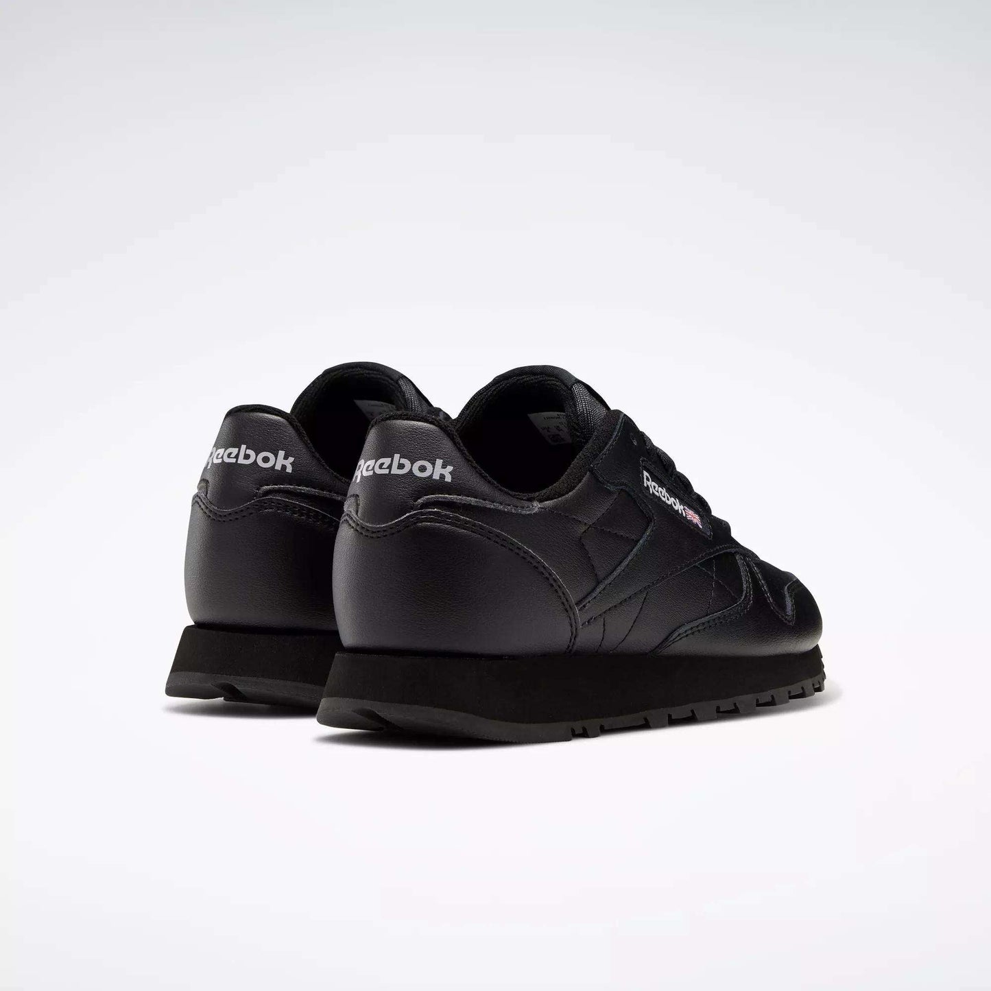 A pair of Reebok Classic Leather Shoes - Big Kids is shown on a white background, angled to display the heel and side with visible Reebok logos—highlighting the timeless Reebok design perfect for boys.