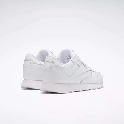 A pair of Reebok Classic Leather Shoes for big kids, shown from the rear on a plain light background. These white sneakers feature a minimal, classic design with the Reebok logo visible on the heel and side.