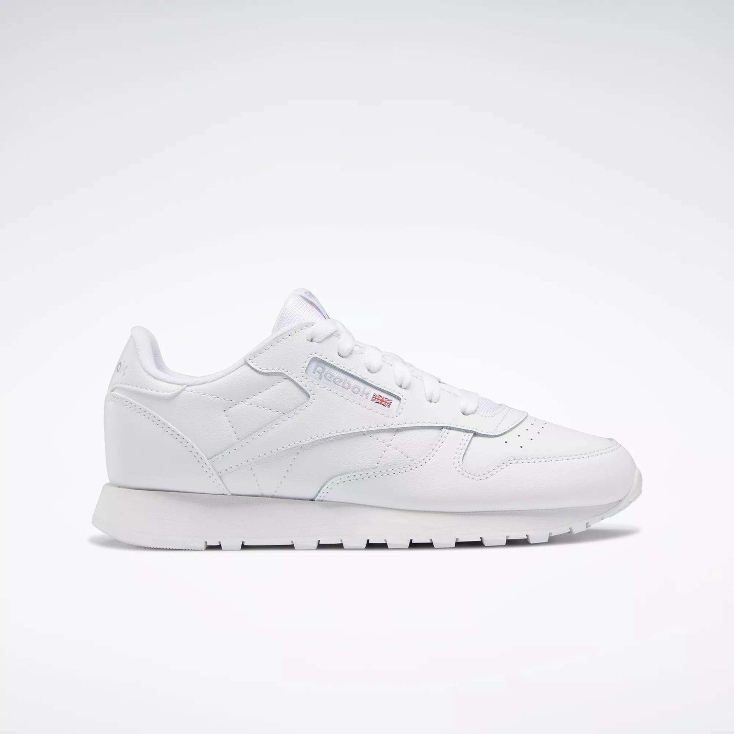 The Reebok Classic Leather Shoes - Big Kids feature an all-white, low-top design with lace-up closure, subtle side branding, and a flat rubber sole—perfect for adding minimalist style to any junior boys' shoe collection.