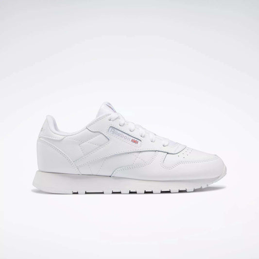 The Reebok Classic Leather Shoes - Big Kids feature an all-white, low-top design with lace-up closure, subtle side branding, and a flat rubber sole—perfect for adding minimalist style to any junior boys' shoe collection.