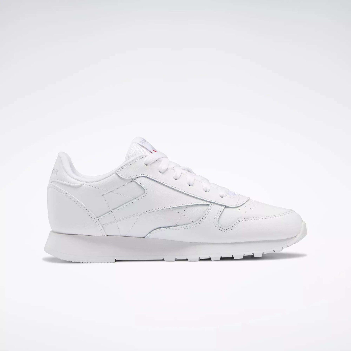 Reebok Classic Leather Shoes - Big Kids: A white, low-profile sneaker with lace-up closure and textured sole, ideal for junior boys—displayed on a plain light background.