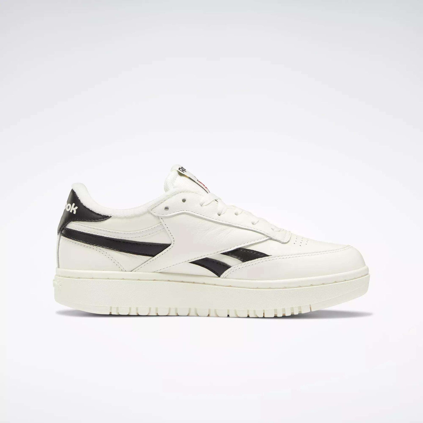 The Reebok Women's Club C Double Revenge Shoes are shown in side view, featuring a white design with black logo and stripes, court-inspired style, and a fashionable double outsole—all set against a plain white background.