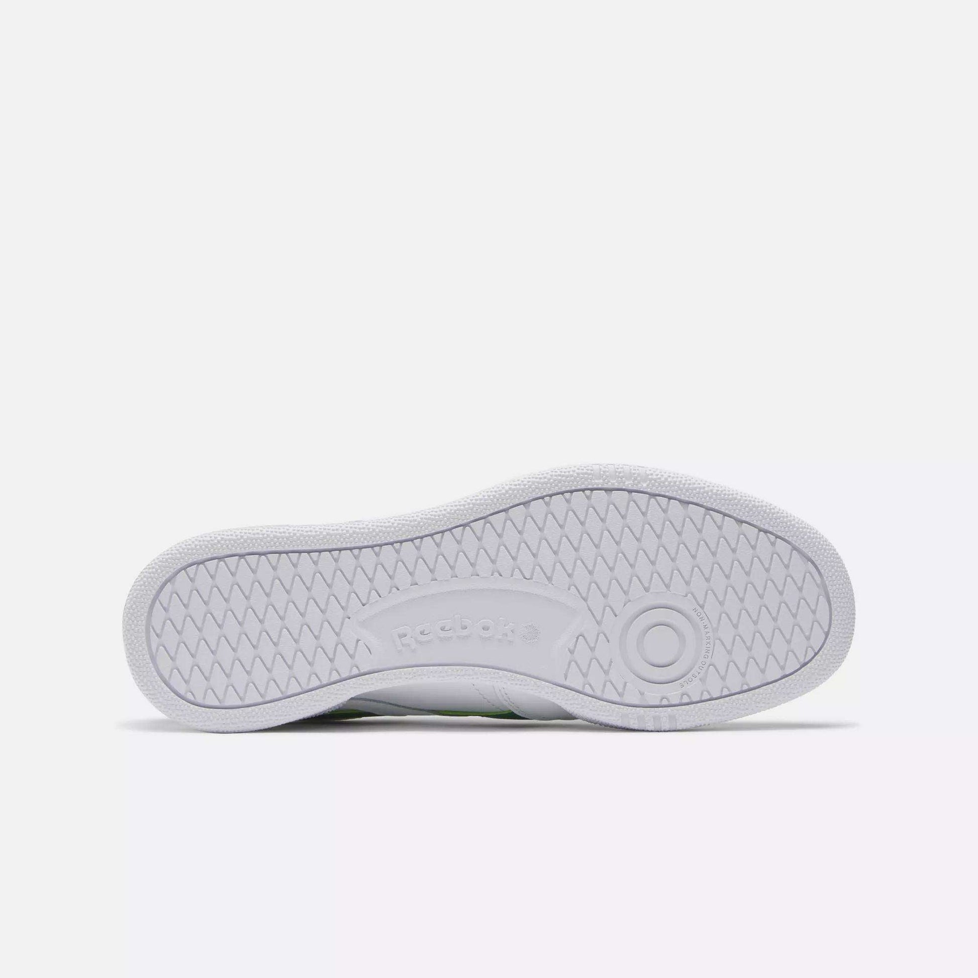 The image displays the white rubber sole of a Reebok Club C Revenge Shoes, viewed from below. It features a herringbone tread pattern and an embossed Reebok logo at the center.