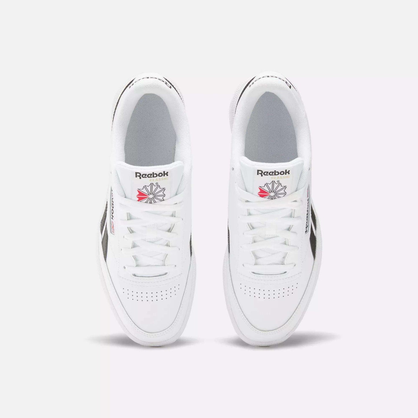 A top view of the Reebok Club C Revenge Shoes shows white trainers with black side accents and the Reebok logo in red and gray on each tongue.