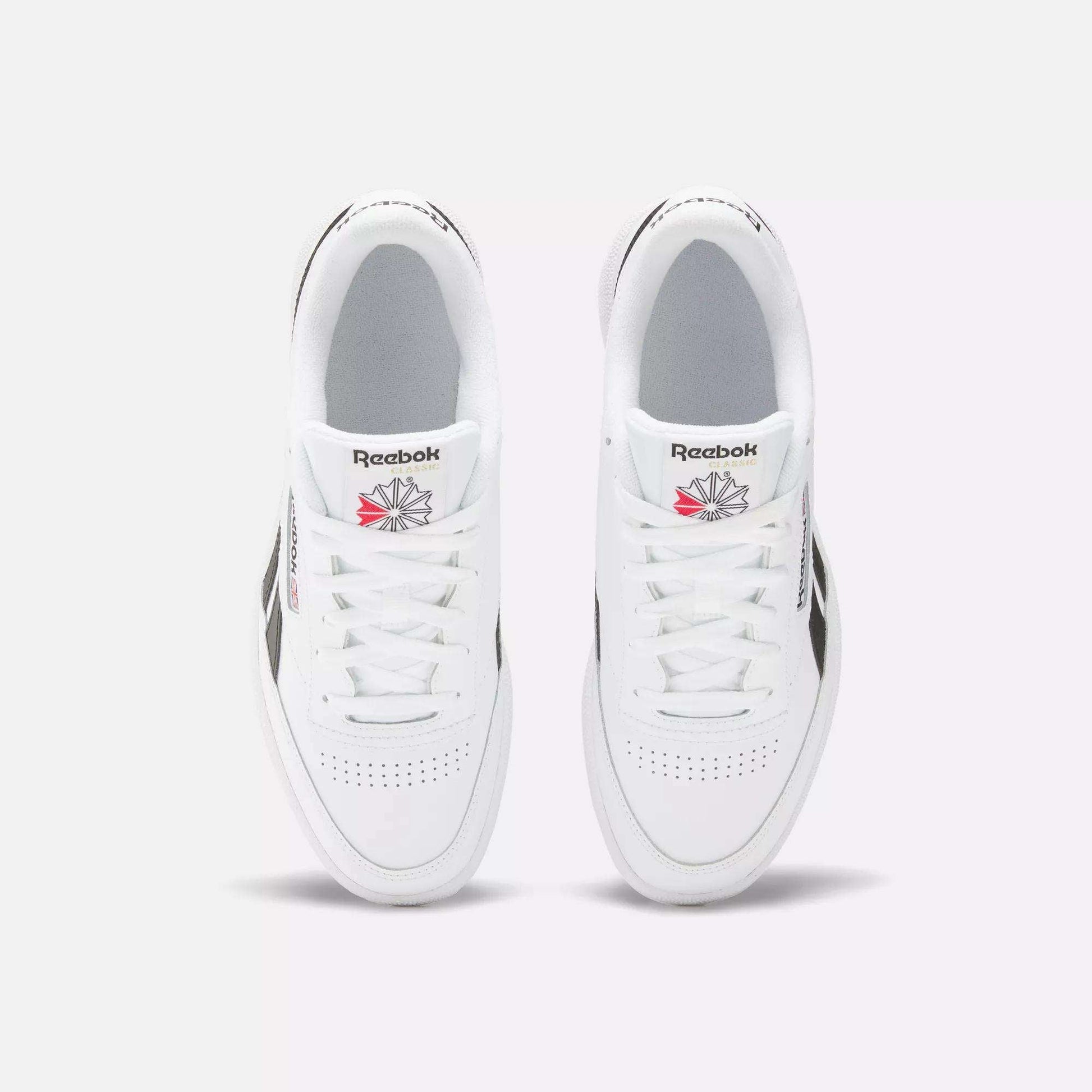 A top view of the Reebok Club C Revenge Shoes shows white trainers with black side accents and the Reebok logo in red and gray on each tongue.