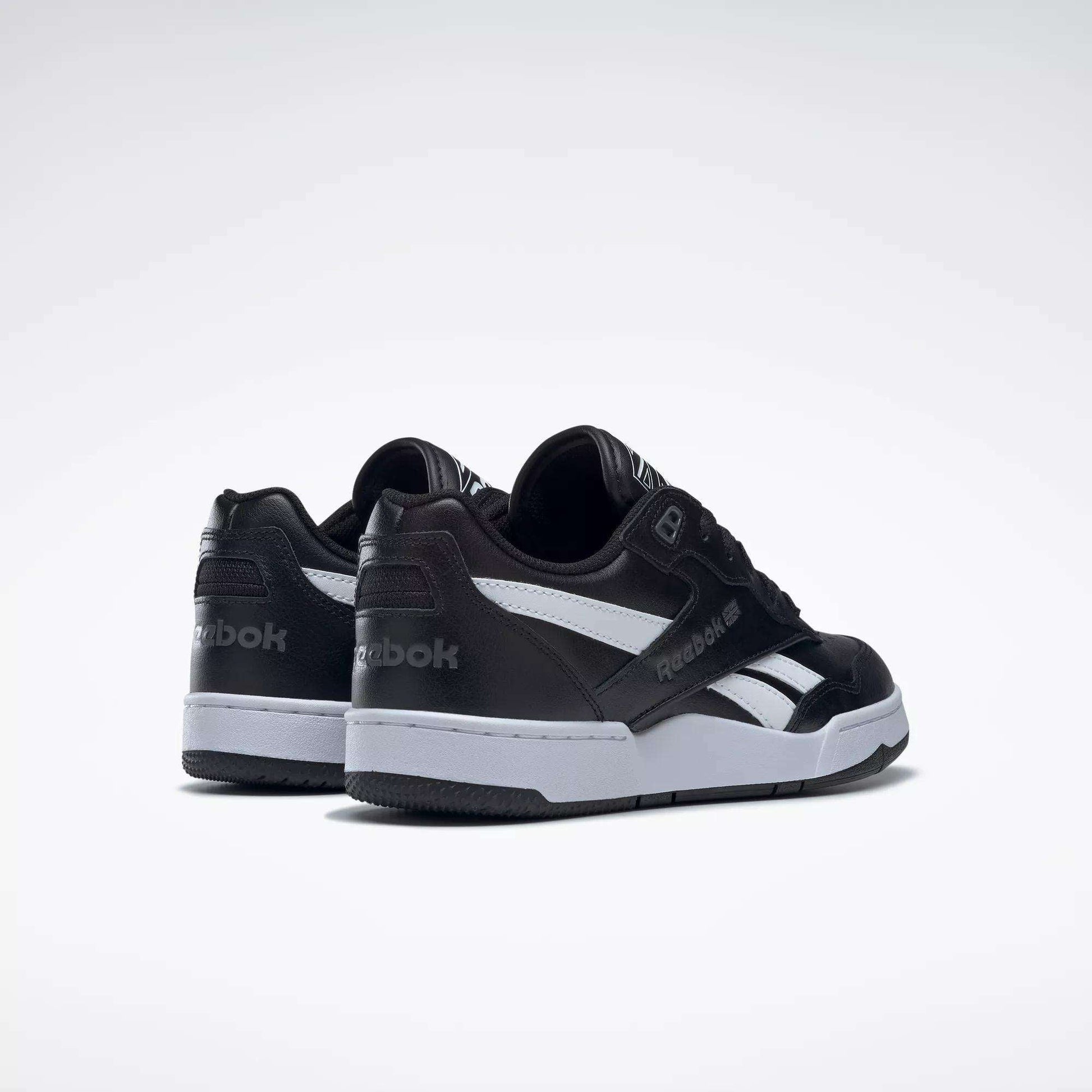 A pair of Reebok BB 4000 II Shoes in black leather with white soles and side stripes are shown on a plain white background, angled to display the back and side views.
