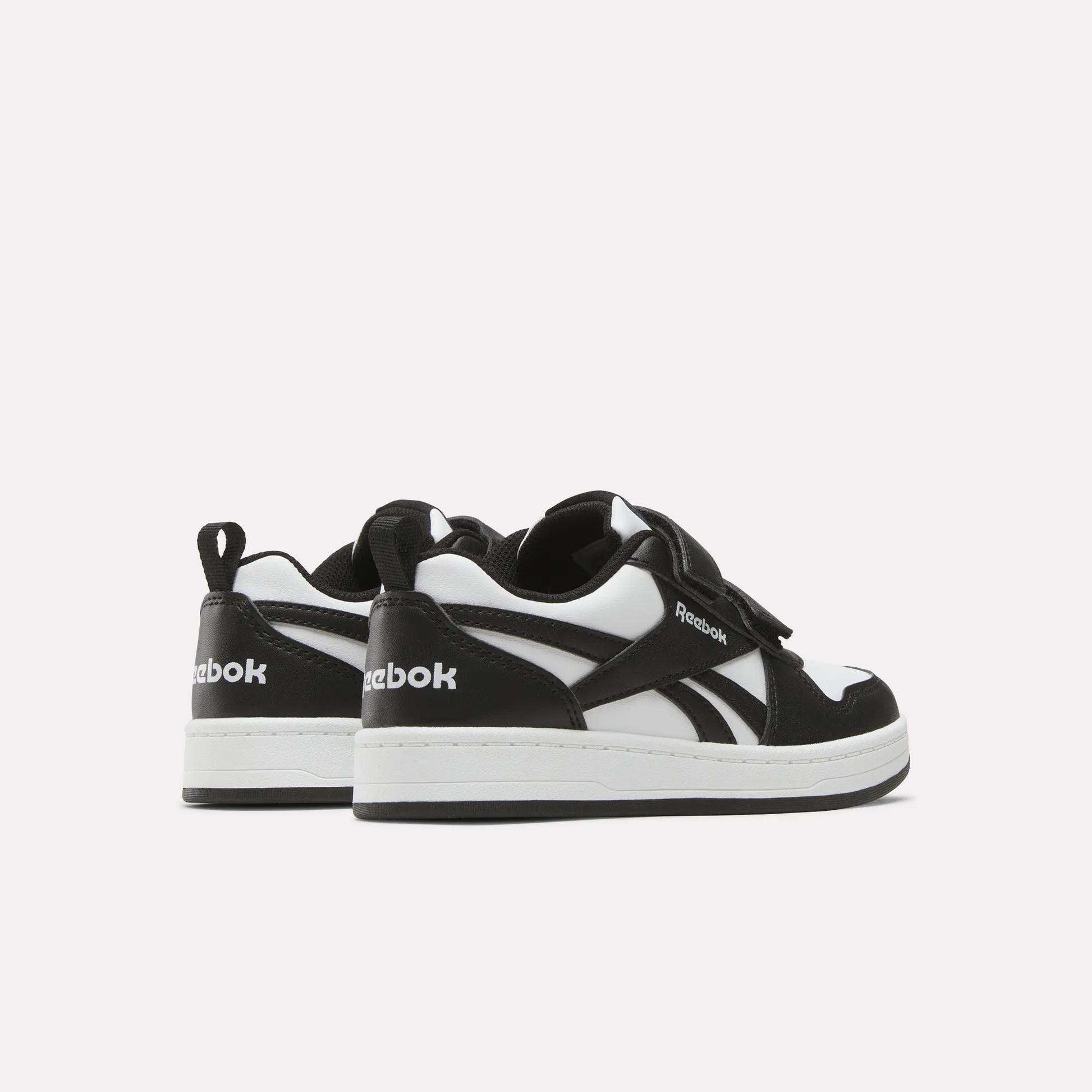Kids' Reebok Royal Prime 2 Shoes by Reebok in black and white, featuring white soles, hook-and-loop straps, and the Reebok logo on the side and heel, shown against a plain light background.