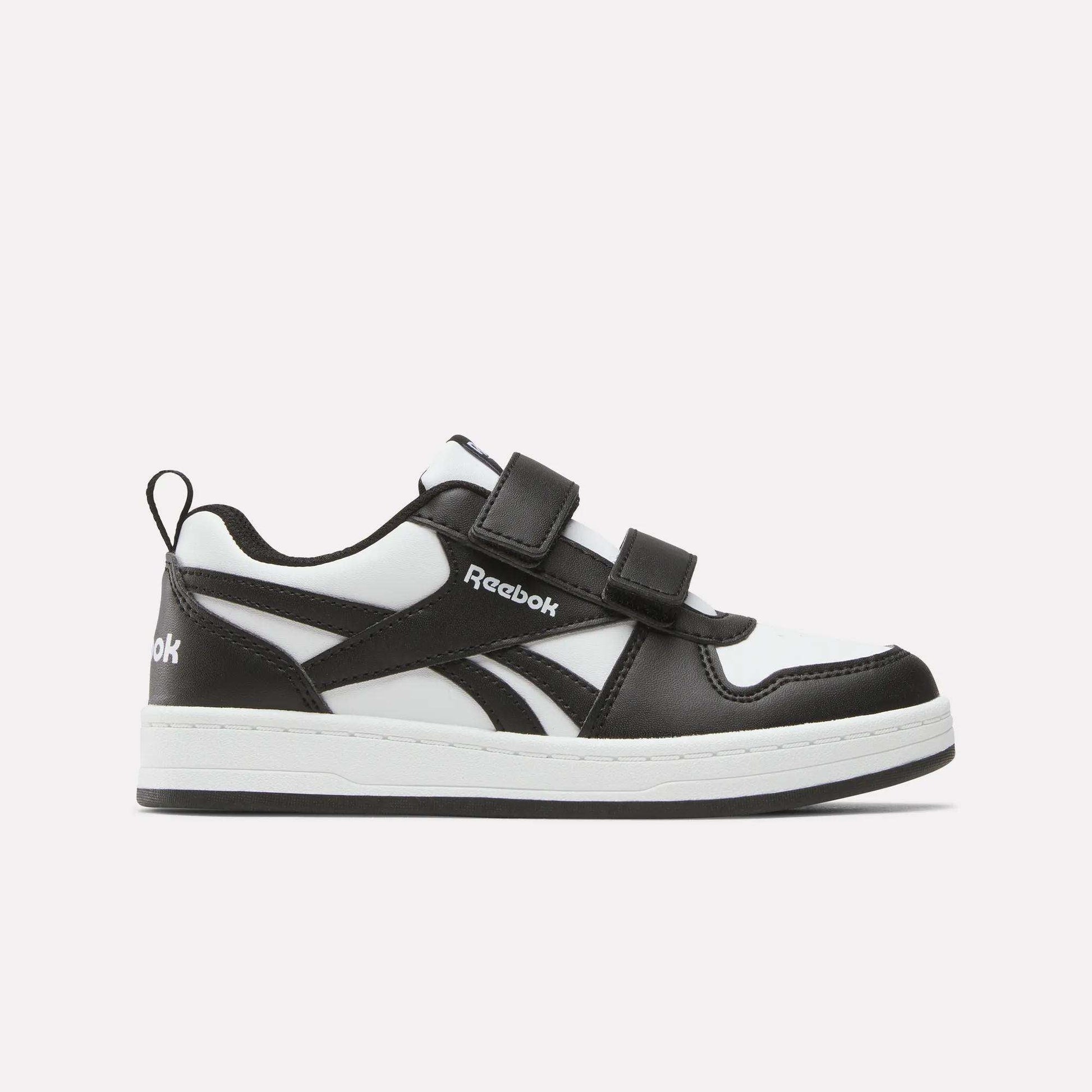 The Kids' Reebok Royal Prime 2 Shoes by Reebok are black and white sneakers featuring two hook-and-loop straps, a white sole, and the Reebok logo on the side, shown against a plain light background.