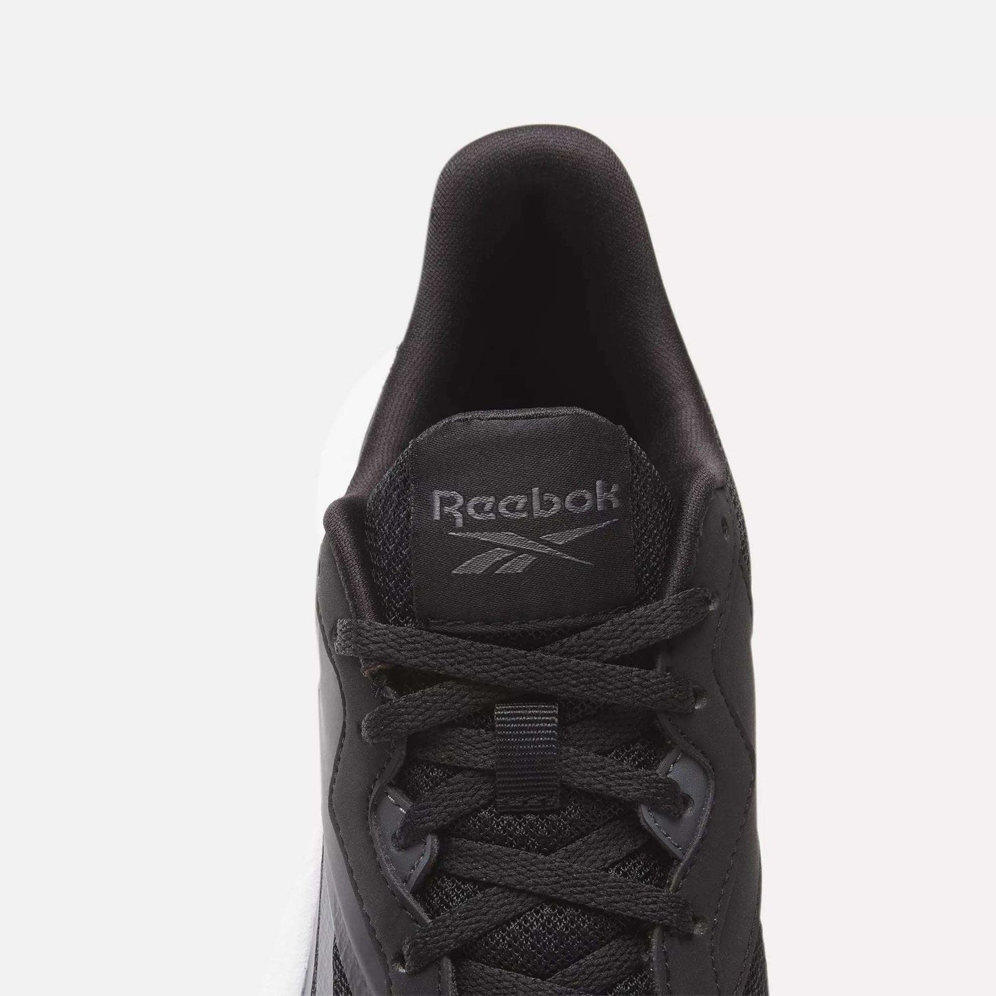 Top view of a black Women's Energen Lux Running Shoe by Reebok with black laces, mesh fabric, and a gray Reebok logo on the tongue. Set against a plain white background.